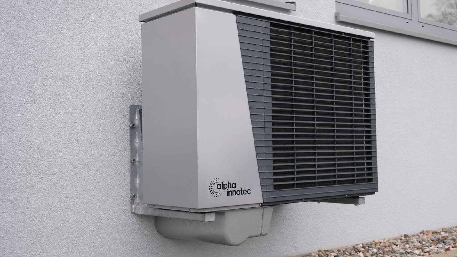Unité extérieure d'une pompe à chaleur air-eau fixée sur le mur d'une maison